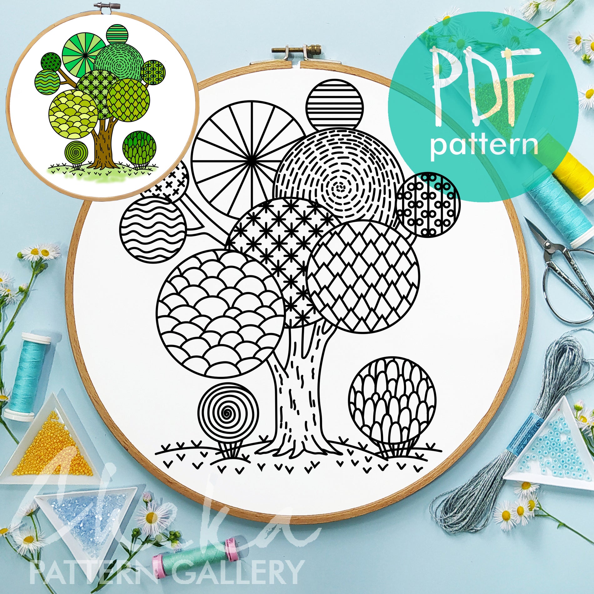 Embroidery hoop with a tree pattern, surrounded by sewing supplies on a light blue background.