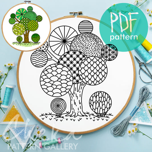 Embroidery hoop with a tree pattern, surrounded by sewing supplies on a light blue background.