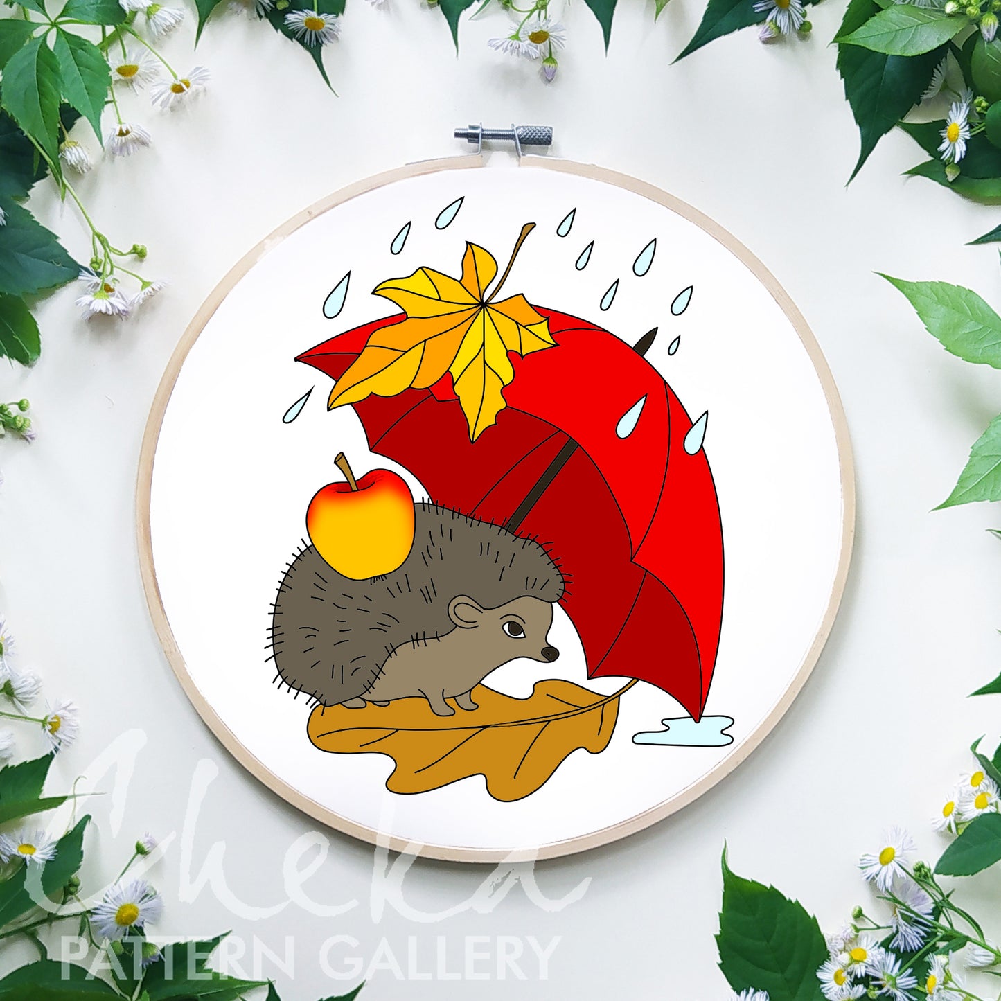 Embroidery hoop with a hedgehog holding a red umbrella and an apple, surrounded by leaves and flowers.