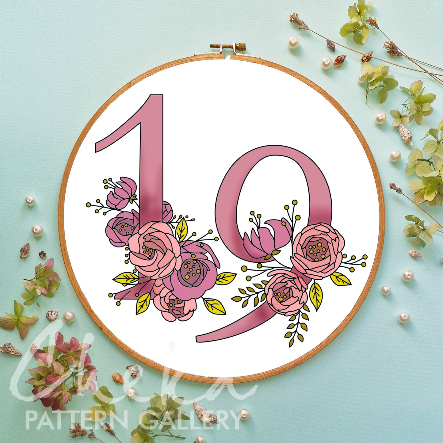 Floral number '10' design in an embroidery hoop on a light blue background with decorative elements.