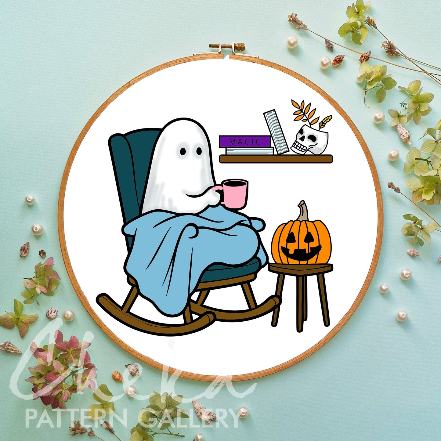 Embroidery hoop with a ghost character drinking coffee, surrounded by decorative elements on a light blue background.