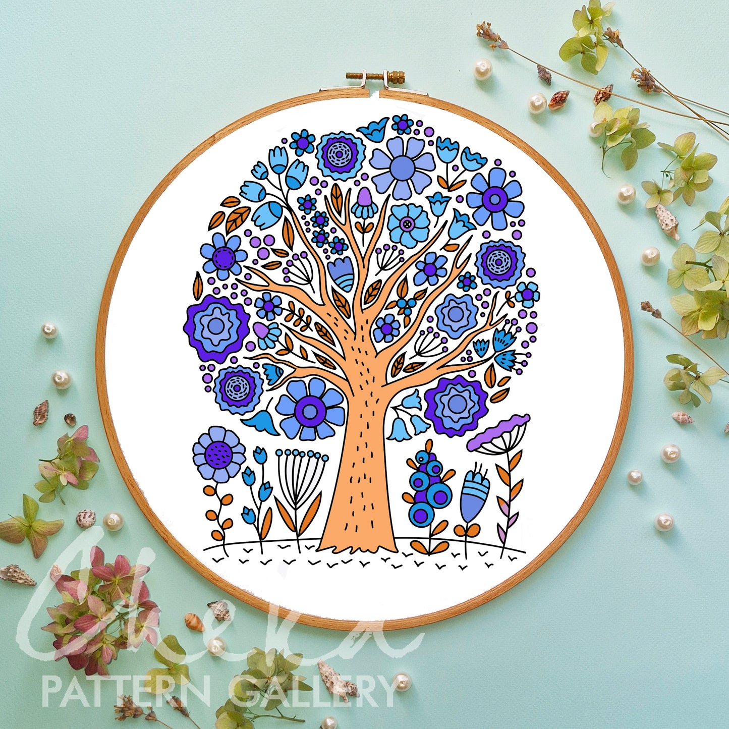 Embroidery hoop with a colorful floral tree design on a light blue background.