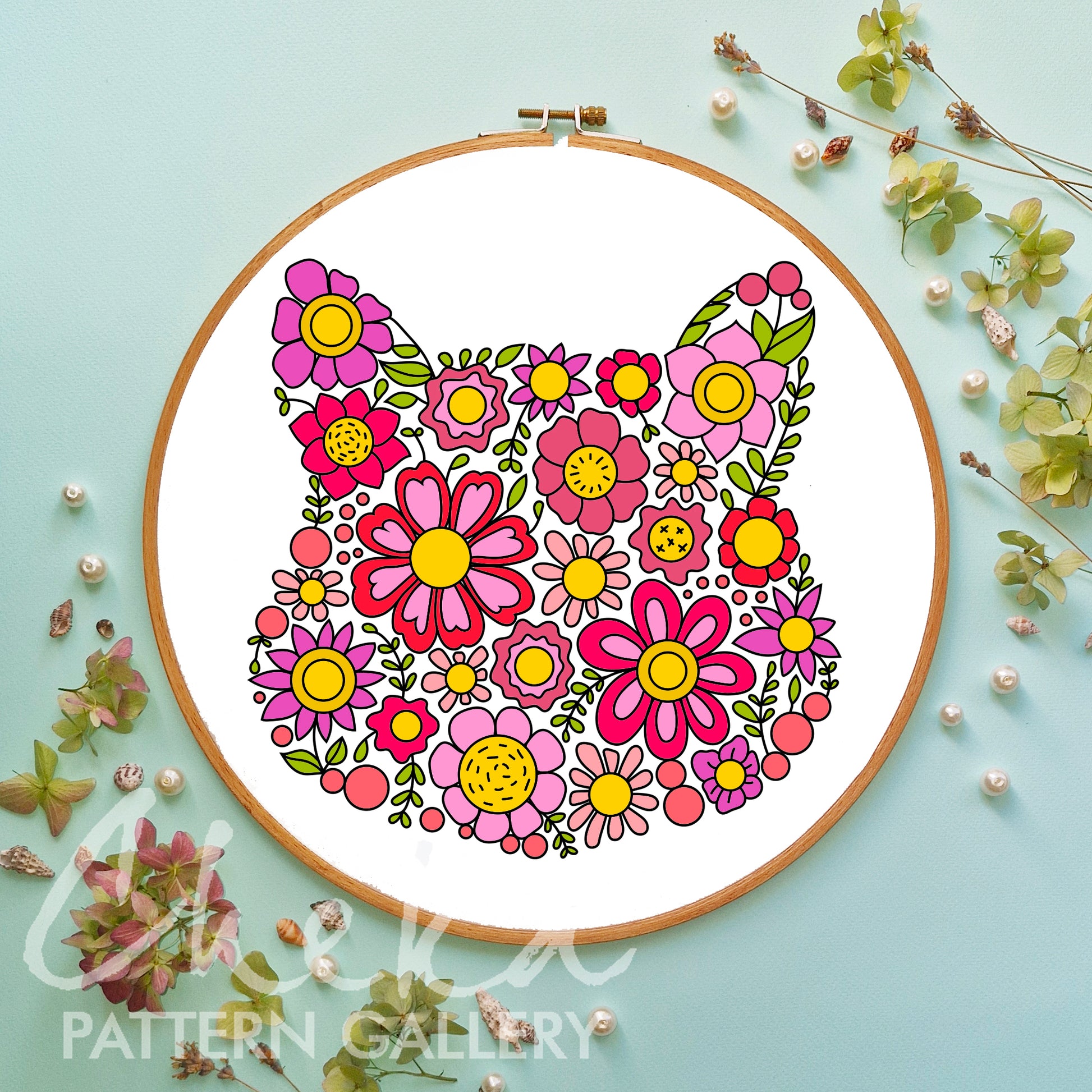 Floral pattern in an embroidery hoop on a light blue background with decorative elements. cat portrait, floral ebroidery